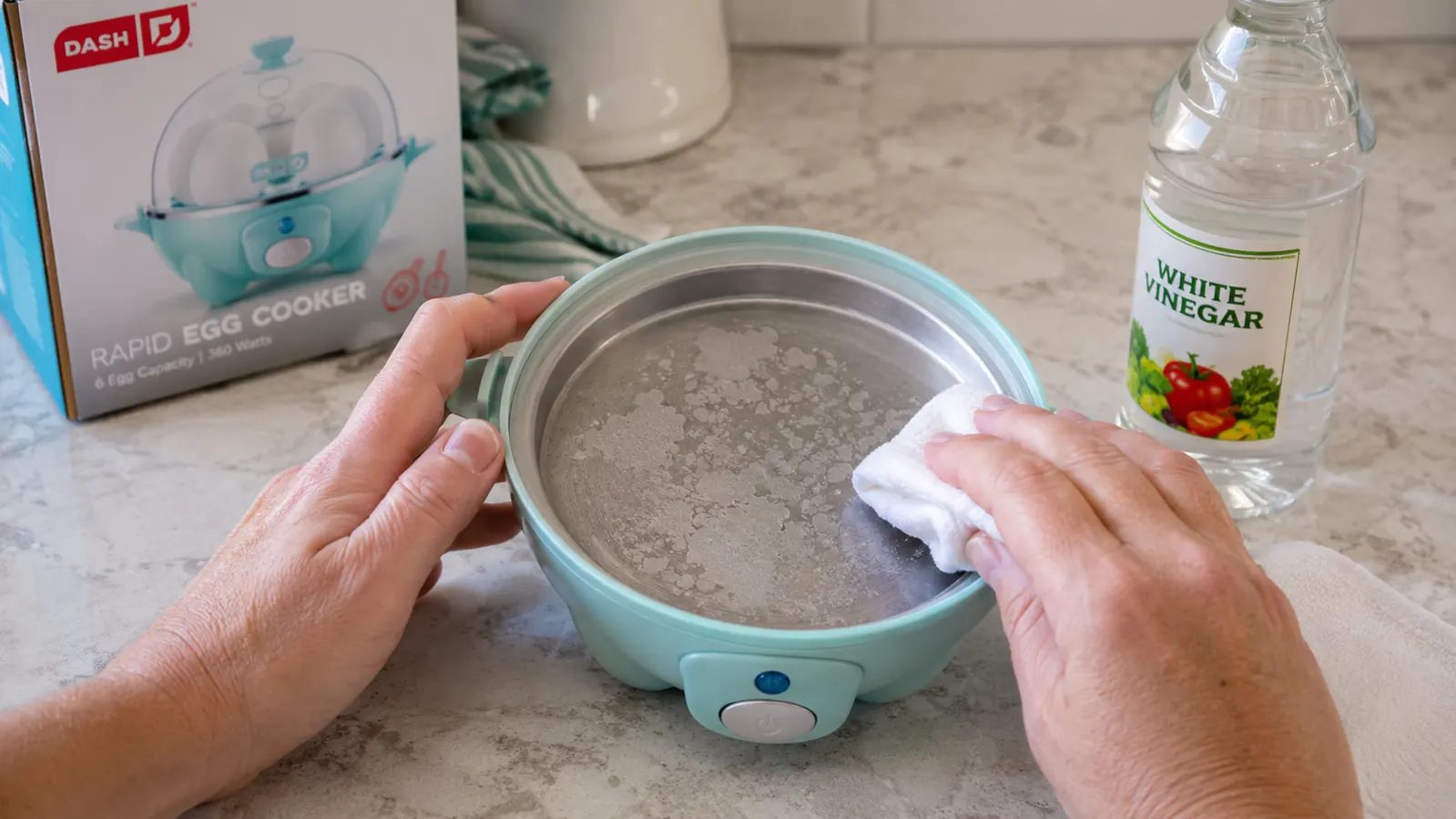 Mineral buildup on the Dash egg cooker heating plate shown next to a cloth with white vinegar for cleaning