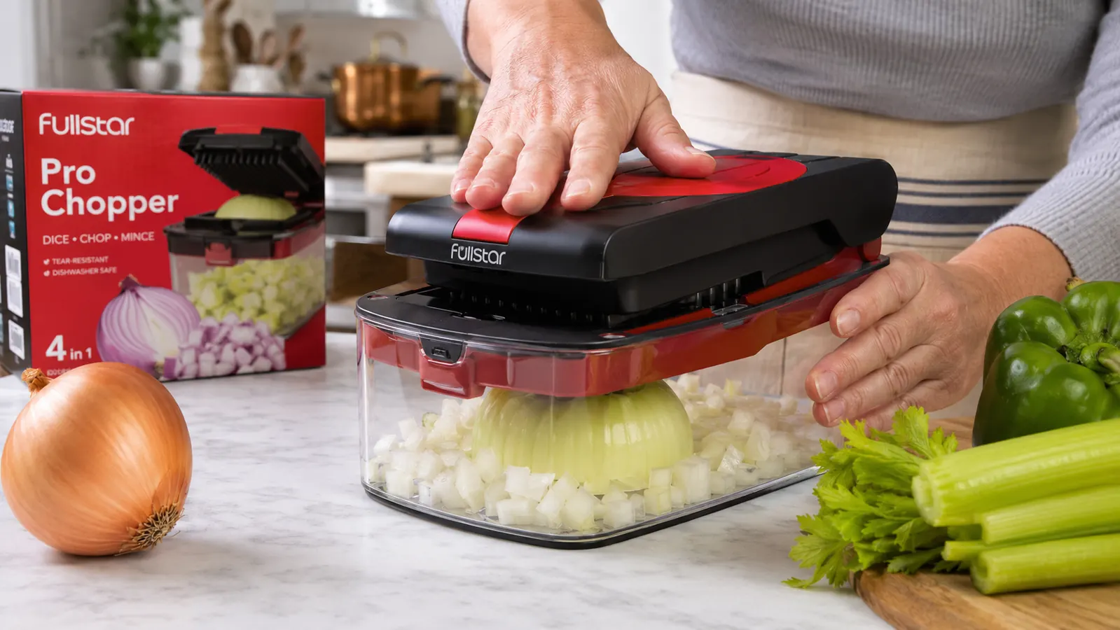 Hands pressing the Fullstar Pro Chopper down onto a halved onion over a clear collection container